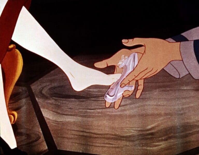 Прекрасный принц кладет Золушке стеклянную туфлю на ногу.